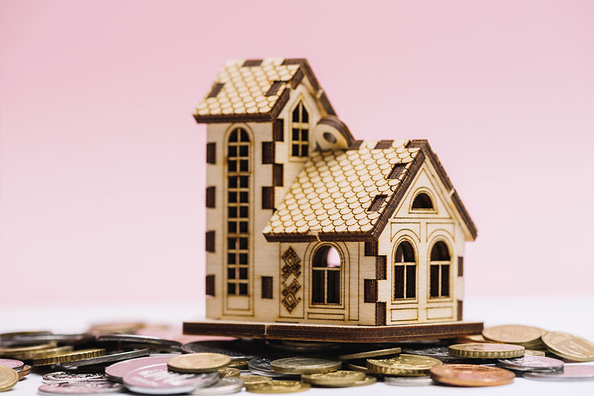 Imagen maqueta de casa sobre un montón de monedas